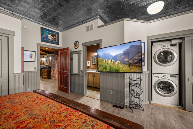 interior space with crown molding, stacked washing maching and dryer, and hardwood / wood-style floors