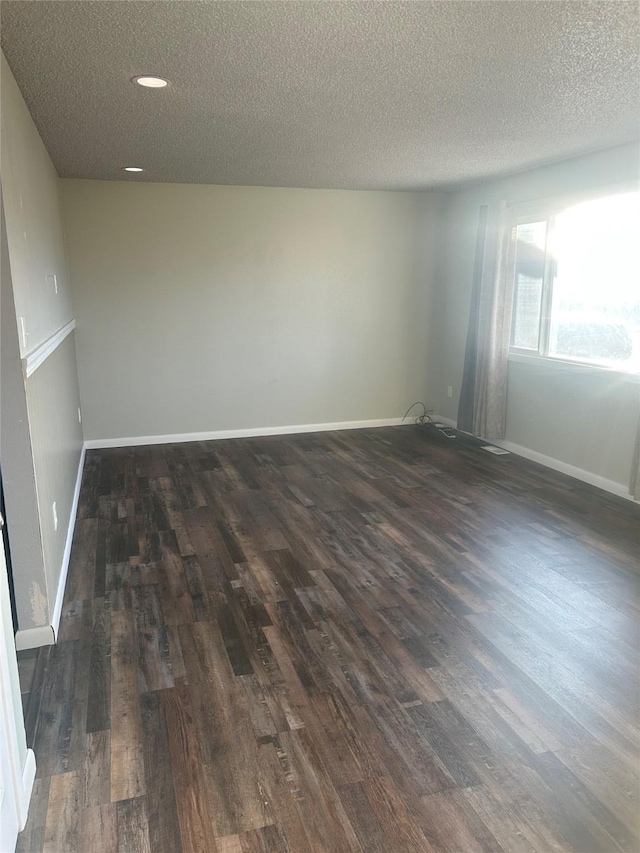 empty room featuring a textured ceiling and dark wood-type flooring