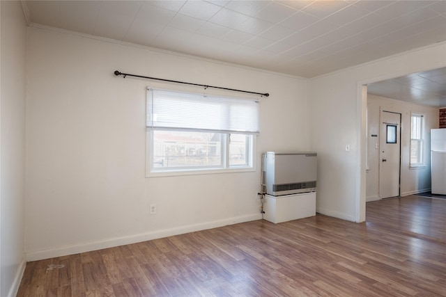 empty room featuring heating unit, crown molding, and hardwood / wood-style flooring