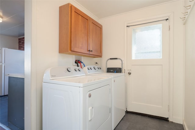 clothes washing area featuring cabinets, dark tile patterned flooring, and washer and clothes dryer