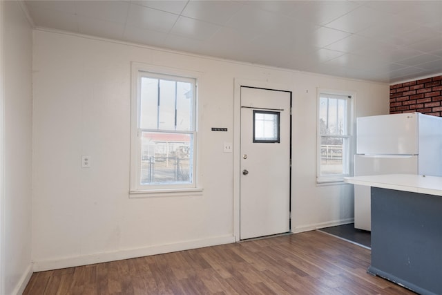 foyer with dark hardwood / wood-style flooring, brick wall, and ornamental molding