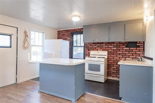 kitchen featuring gray cabinetry, sink, light hardwood / wood-style flooring, brick wall, and white appliances