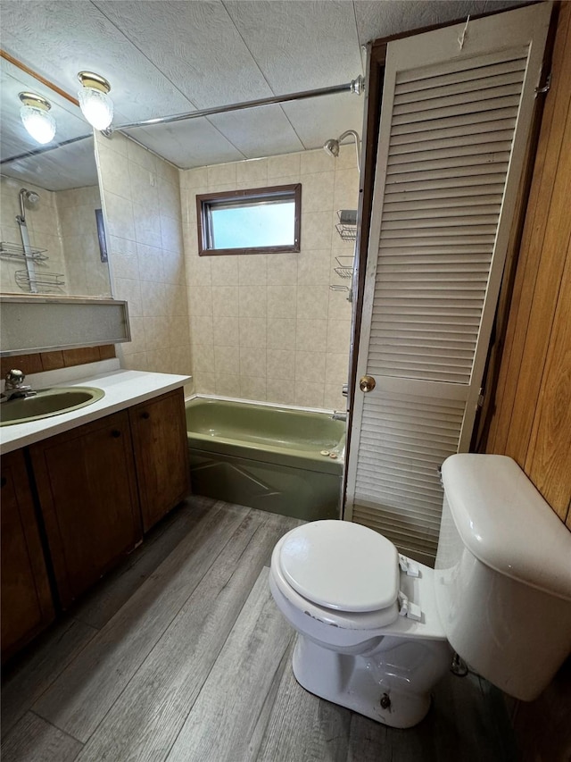 full bathroom with vanity, toilet, wood-type flooring, and tiled shower / bath