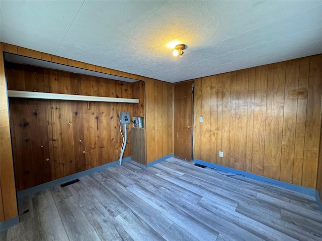 unfurnished room featuring wood walls and light hardwood / wood-style floors