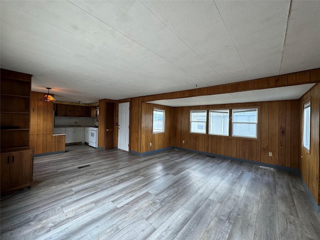 unfurnished living room with wood walls and light hardwood / wood-style floors