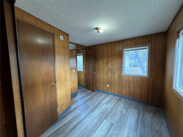 spare room featuring a textured ceiling, light wood-type flooring, and wooden walls