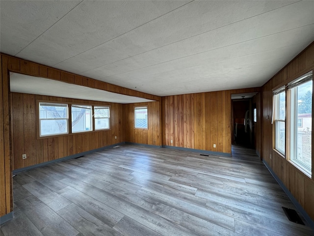 unfurnished room featuring wood walls and light wood-type flooring