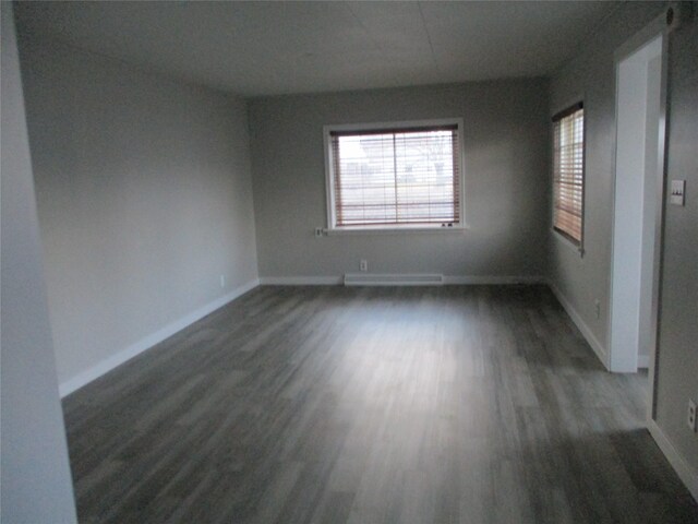 spare room with a baseboard radiator and dark hardwood / wood-style flooring