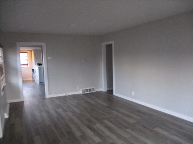 unfurnished room with a wealth of natural light, a baseboard heating unit, and dark hardwood / wood-style floors