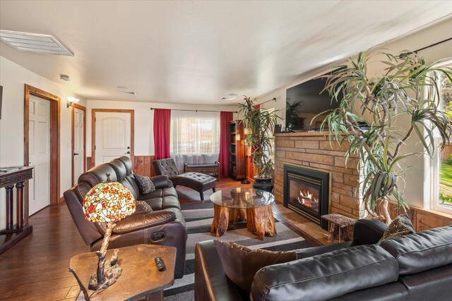 living room with plenty of natural light, a fireplace, and dark wood-type flooring