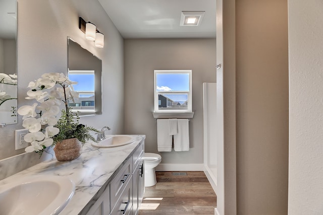 bathroom with wood-type flooring, vanity, toilet, and a healthy amount of sunlight