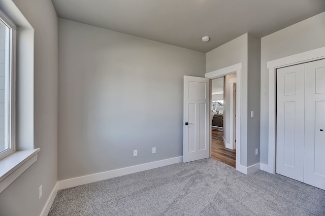 unfurnished bedroom featuring a closet and light colored carpet