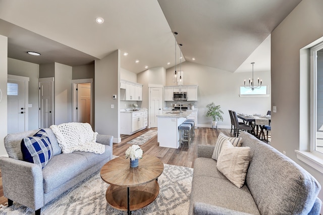 living room with hardwood / wood-style flooring, a notable chandelier, and lofted ceiling