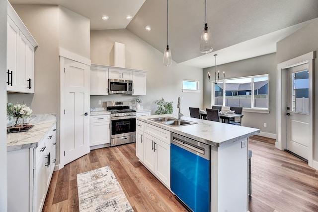 kitchen featuring appliances with stainless steel finishes, sink, a center island with sink, white cabinetry, and hanging light fixtures