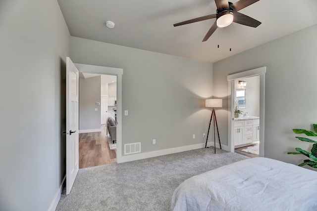 bedroom featuring light carpet, connected bathroom, ceiling fan, and sink