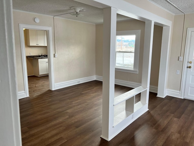 spare room with ceiling fan, dark hardwood / wood-style flooring, a textured ceiling, and crown molding