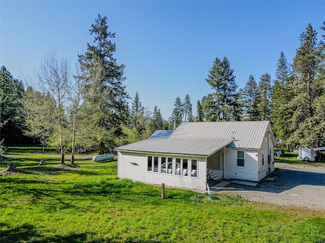 exterior space featuring a yard, metal roof, and gravel driveway