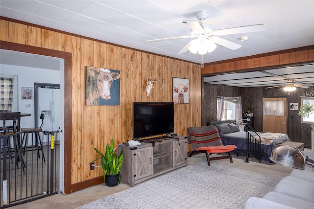 living room featuring light carpet, ceiling fan, and wood walls