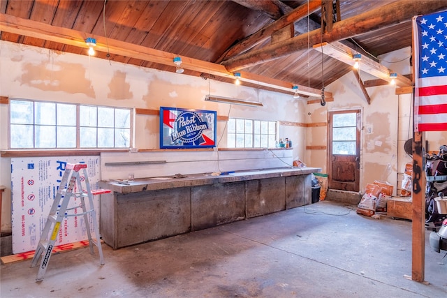 miscellaneous room with unfinished concrete floors, wood ceiling, and lofted ceiling with beams
