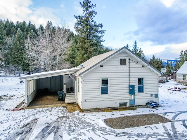 snow covered rear of property featuring a carport