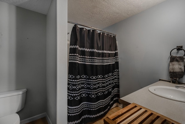 bathroom featuring vanity, a textured ceiling, toilet, and walk in shower