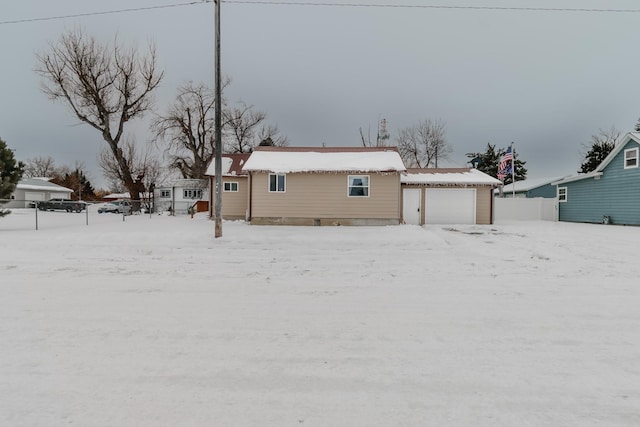 snow covered back of property featuring a garage and an outdoor structure