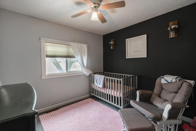 bedroom featuring a crib, a textured ceiling, and ceiling fan