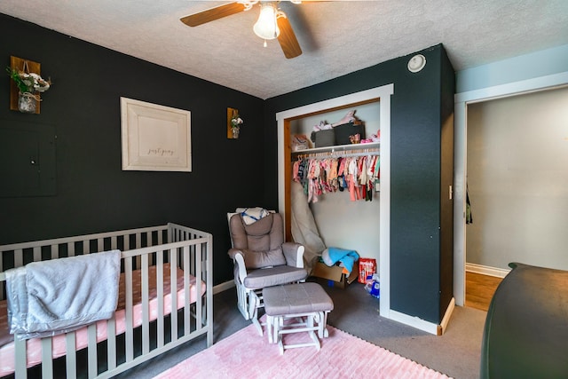 bedroom with a textured ceiling, a nursery area, a closet, and ceiling fan