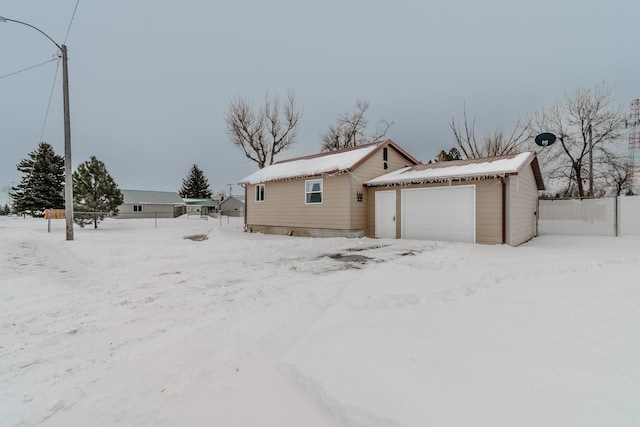 view of snow covered exterior with a garage and an outbuilding