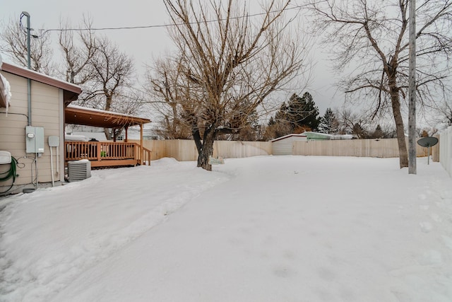 yard layered in snow featuring central AC unit and a wooden deck