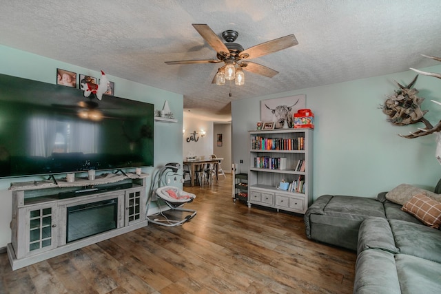 living room featuring wood-type flooring, a textured ceiling, and ceiling fan