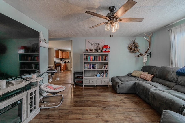 living room featuring ceiling fan, dark wood-type flooring, and a textured ceiling