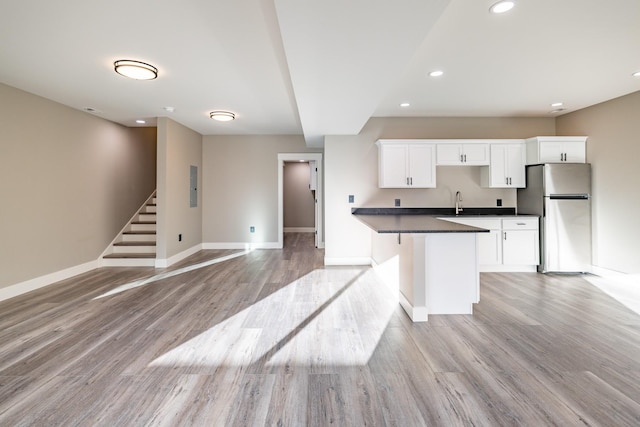 kitchen featuring stainless steel fridge, light hardwood / wood-style floors, white cabinetry, and a kitchen breakfast bar