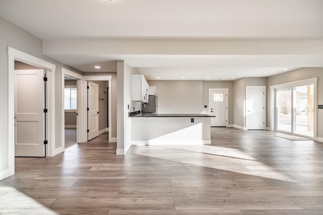 kitchen featuring white cabinets, stainless steel fridge, light wood-type flooring, and kitchen peninsula