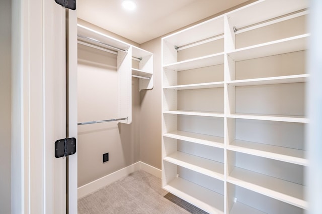 walk in closet featuring light colored carpet