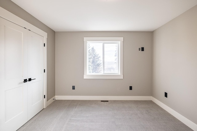 unfurnished bedroom featuring light carpet and a closet