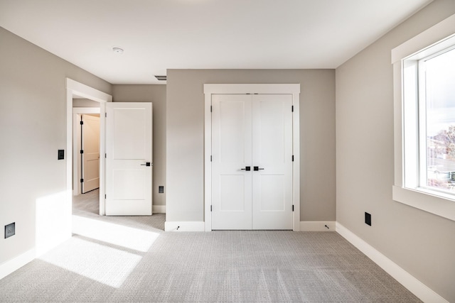 unfurnished bedroom featuring light colored carpet and a closet