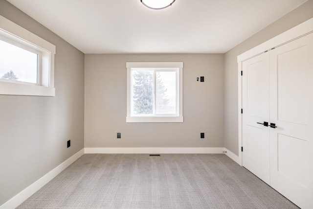 interior space featuring multiple windows, light carpet, and a closet