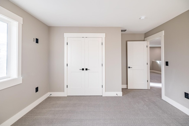 unfurnished bedroom with light carpet and a closet