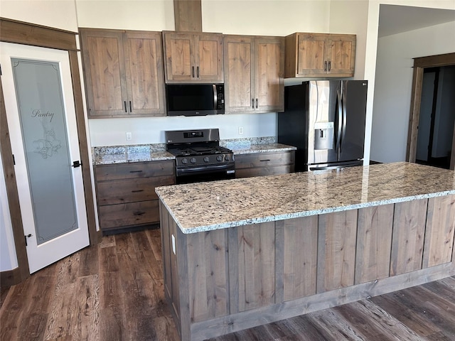 kitchen featuring light stone countertops, dark hardwood / wood-style flooring, and appliances with stainless steel finishes