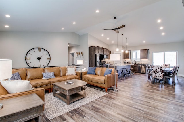 living room with light hardwood / wood-style floors, ceiling fan, lofted ceiling, and sink