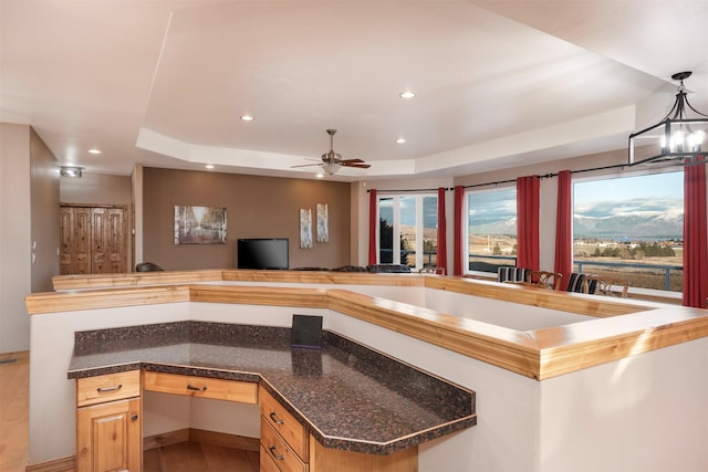 kitchen with ceiling fan, decorative light fixtures, light brown cabinetry, and a tray ceiling