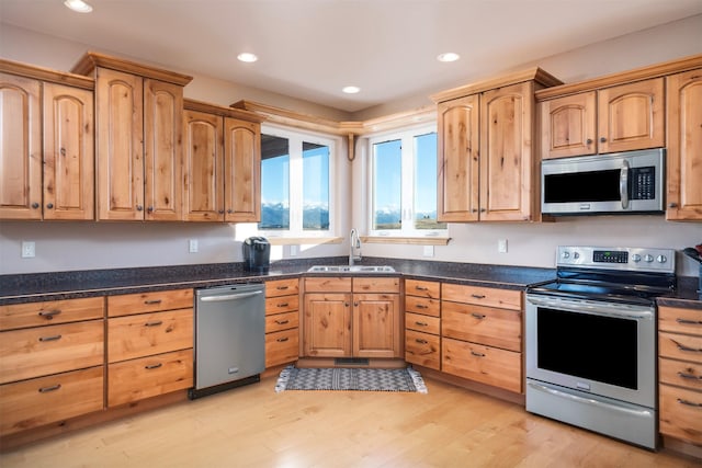 kitchen with light hardwood / wood-style floors, sink, stainless steel appliances, and dark stone counters