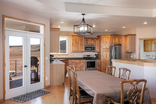 kitchen featuring sink, an inviting chandelier, light hardwood / wood-style floors, pendant lighting, and appliances with stainless steel finishes