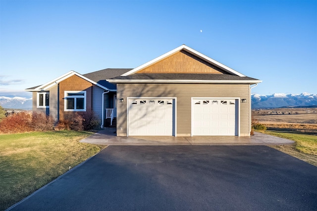 single story home featuring a mountain view, a garage, and a front lawn