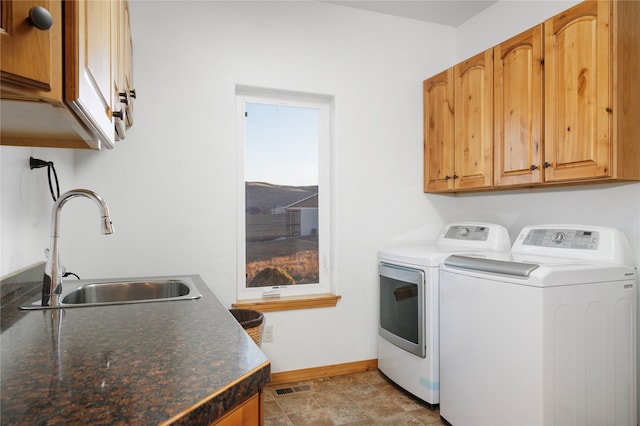 washroom with cabinets, washing machine and dryer, and sink