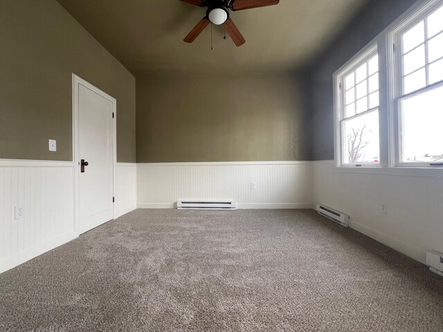 empty room with carpet flooring, a baseboard radiator, and ceiling fan