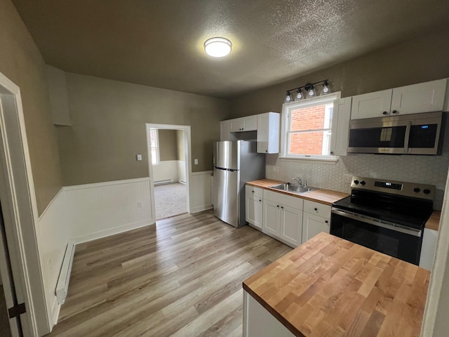 kitchen with sink, light hardwood / wood-style flooring, butcher block countertops, white cabinets, and appliances with stainless steel finishes