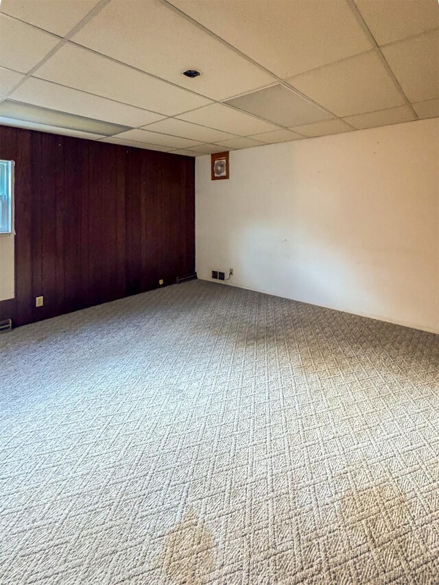 basement with a paneled ceiling and wooden walls