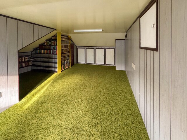 interior space with lofted ceiling, carpet floors, and wooden walls